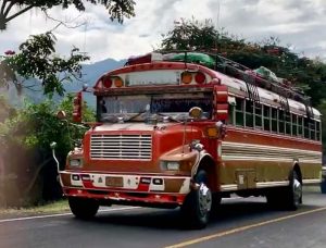 A colorful red bus with luggage on top. faq
